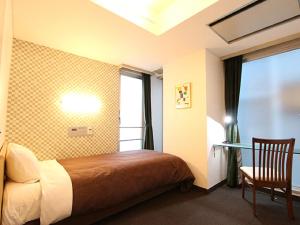 a bedroom with a bed and a chair and a window at HOTEL LiVEMAX BUDGET Korakuen in Tokyo