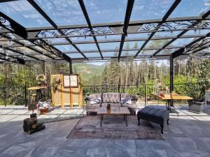 a glassconservatory with a couch and a table at Арборетум Вила & Ресторант in Teteven