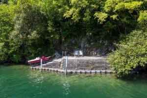 un molo con due sedie e una barca in acqua di Reka-Ferienanlage Gandria a Gandria