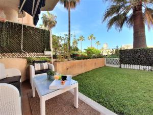 a patio with a table and a lawn with palm trees at COSTA LAGO BEACH in Torremolinos
