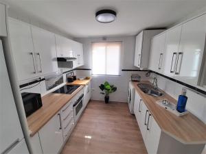 cocina con armarios blancos, fregadero y ventana en COSTA LAGO BEACH en Torremolinos