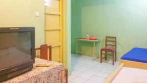 ein Wohnzimmer mit einem TV und einem Tisch mit einem Stuhl in der Unterkunft Hotel Jaya Kusuma near Candi Prambanan Mitra RedDoorz in Prambanan