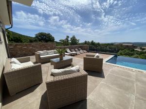 a patio with wicker furniture and a swimming pool at Tres belle villa neuve vue mer avec piscine chauffee in Sainte-Lucie de Porto-Vecchio