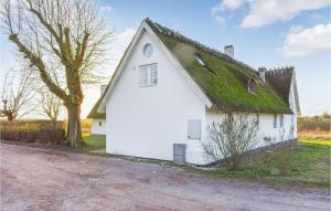 a white barn with a grass roof on a dirt road at Stunning Home In Staffanstorp With Kitchen in Staffanstorp