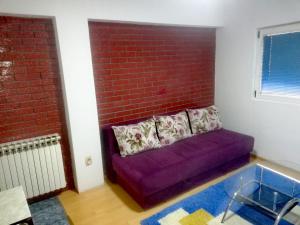 a purple couch in a room with a brick wall at Apartman Centar in Foča