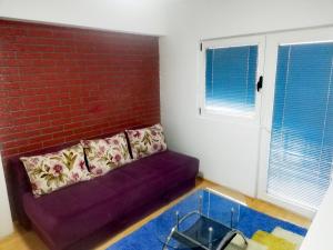 a purple couch in a room with a brick wall at Apartman Centar in Foča