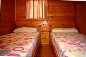 two beds in a log cabin with a window at Camping Bungalows Sol D´Or in Peniscola