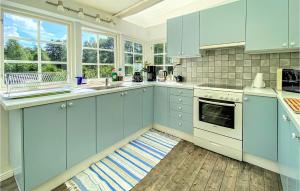 Nice Home In ngelholm With Wifi في أنغيلهولم: مطبخ مع دواليب زرقاء وارضية خشبية