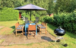 una parrilla con mesa y sillas bajo una sombrilla en Nice Home In Ängelholm With Wifi, en Ängelholm