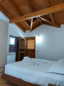 a bedroom with a bed with white sheets and wooden ceilings at Vila Green Relax in Vlorë