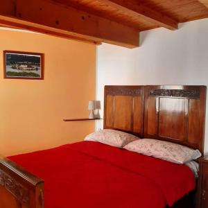 Schlafzimmer mit einem roten Bett mit einem Kopfteil aus Holz in der Unterkunft Casa Marconi Casa Vacanze in Cesara