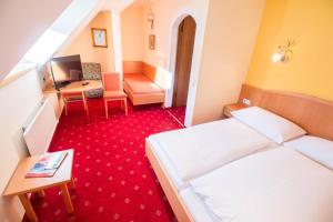 Pokój hotelowy z 2 łóżkami, biurkiem i telewizorem w obiekcie Hotel Weissenstein w mieście Sankt Michael im Lungau +37 zdjęć