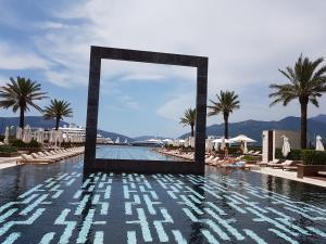 a pool at a resort with palm trees and a mirror at Wisteria in Tivat