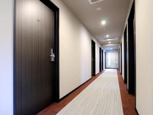 a hallway with black doors and a white carpet at HOTEL LiVEMAX Ueno-Ekimae in Tokyo