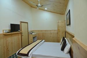 een slaapkamer met een bed en een flatscreen-tv bij Kasauli Nature Inn in Kasauli