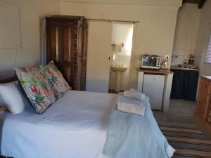 1 dormitorio con 1 cama blanca grande y cocina en Rosebury Cottage, en Underberg