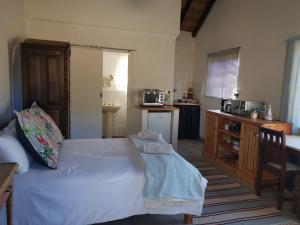 1 dormitorio con 1 cama blanca y cocina en Rosebury Cottage, en Underberg