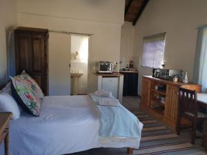 ein Schlafzimmer mit einem weißen Bett und einer Küche in der Unterkunft Rosebury Cottage in Underberg