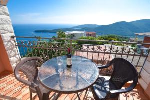 a glass table with a bottle of wine on a balcony at Apartments Villa Sveti Nikola in Budva