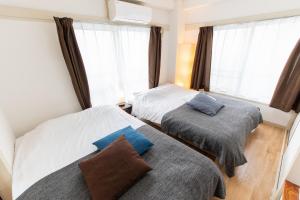 two beds in a room with a window at LUANAHOTEL IN WASEDA in Tokyo