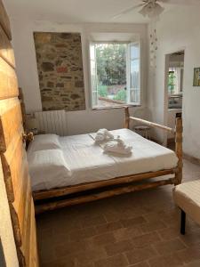 a bedroom with a wooden bed with white sheets and a window at Agriturismo Baratti in Baratti