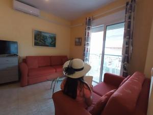 a woman wearing a hat sitting on a couch in a living room at Gianna's House in Paradisos