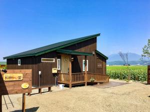 a large wooden building with a porch in a field at Country Cottage Wakiaiai in Nakafurano