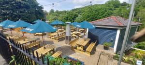 una zona de estar al aire libre con sombrillas azules y bancos de madera. en The Hand Hotel, en Llangollen