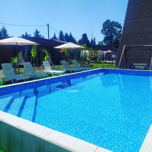 a large blue swimming pool with chairs and umbrellas at Дом Шале Оазис in Pizunda