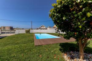 een zwembad in een tuin met een boom bij Viana Fishers House - Amazing Apartments in Front of the Sea in Viana do Castelo