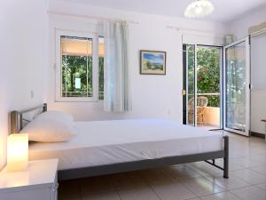 a white bedroom with a large bed and windows at Villa Serena in Mitikas
