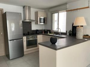 a kitchen with a stainless steel refrigerator and a sink at VILLA OCEANE in San-Nicolao