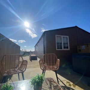 a patio with three chairs and a tiny house at Aintree Lodge - Hot Tub - Northumberland in Swarland