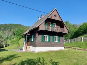 a wooden house with a balcony on a grass field at Knusperhaus Ogris in Trieblach