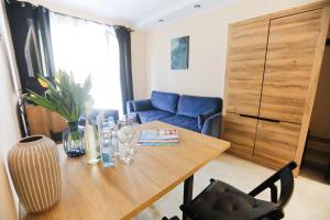 salon z drewnianym stołem i niebieską kanapą w obiekcie M&K Apartamenty Rodzinny, Gdańsk - Wyspa Sobieszewska w Gdańsku