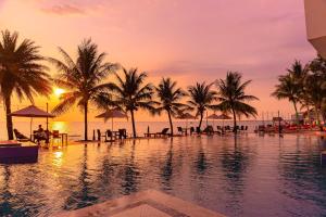 una piscina con palme e l'oceano al tramonto di Sun Viet Resort Phu Quoc a Phu Quoc