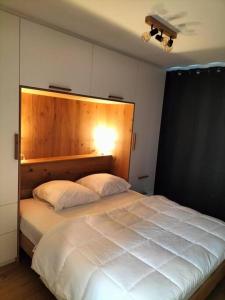 um quarto com uma grande cama branca e uma cabeceira em madeira em Superbe Appartement avec Parking em Malmedy