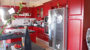 cocina con armarios rojos y nevera de acero inoxidable en Villa Omega Kefalonia en Karavadhos