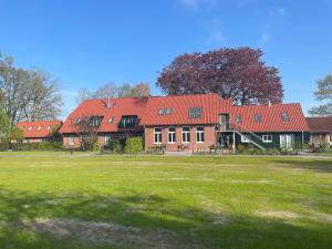 a large building with red roofs in a field at Meine Schule Sehlingen, stilvolle Familien-Unterkunft auf dem Land in Kirchlinteln