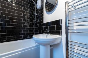 a bathroom with a sink and a mirror and a tub at Tiddles in St Ives