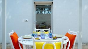 una mesa blanca con sillas y una mesa con gafas. en Casetta La Conchiglia, en Villanova di Ostuni