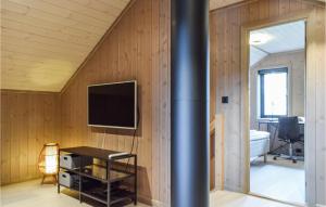 een kamer met houten lambrisering en een muur met een televisie bij Stunning Home In Vatnestrm With Sauna 