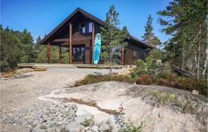 a log cabin in the woods with a large rock at Stunning Home In Vatnestrøm With Sauna in Skreeros +21 photos