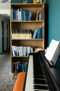 a piano in front of a book shelf with books at HOTEL SØMA Nuuk in Nuuk