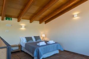 a bedroom with a bed with blue sheets and a wooden ceiling at casa La Vera rural in Talaveruela