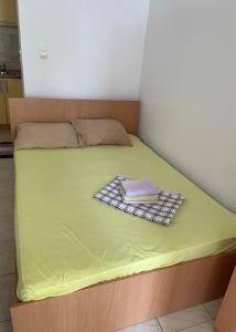 a bed with a green sheet and a book on it at Apartments Sveti Stefan-Marko in Sveti Stefan