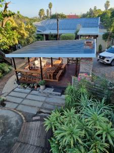 a pavilion with a blue roof in front of a house at The Birdhouse Bed & Breakfast #NO Loadshedding #Solar Energy in Gonubie