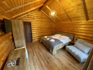 a bedroom in a log cabin with a bed and a couch at Complex Adora in Bicaz