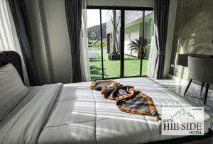 Kata Hillside Hotel في شاطئ كاتا: سرير في غرفة نوم مع نافذة كبيرة