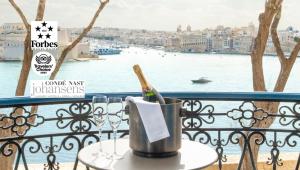 a bucket with a bottle of wine on a table on a balcony at Iniala Harbour House in Valletta